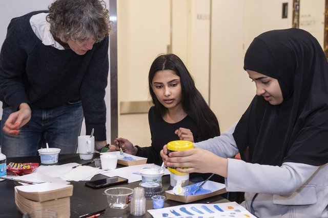 Kvinde hjælper piger med maleri