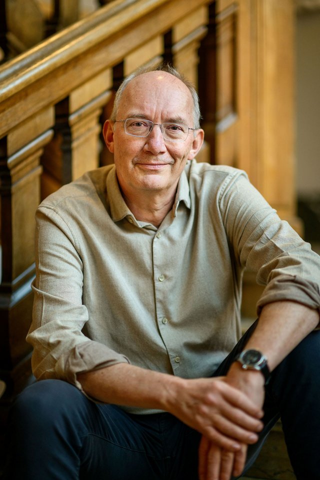 Portræt af person, der sidder på en trappe med gelænder i baggrunden.