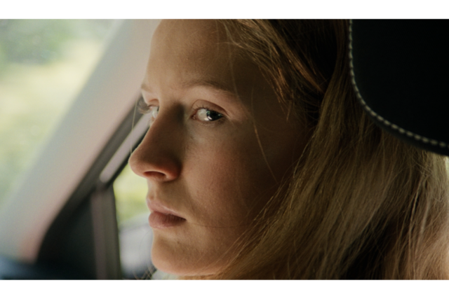 Kvinde i bil, som kigger i kameraet