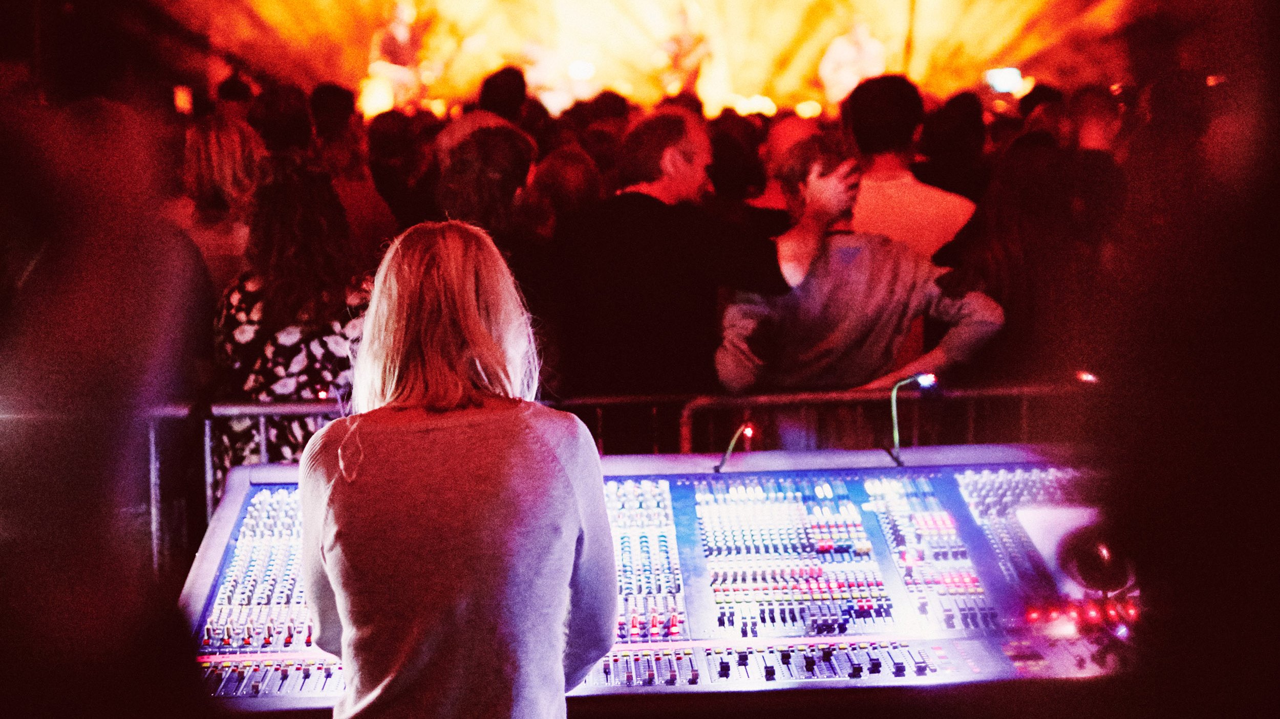 En der står ved en mixerpult med publikum i foran