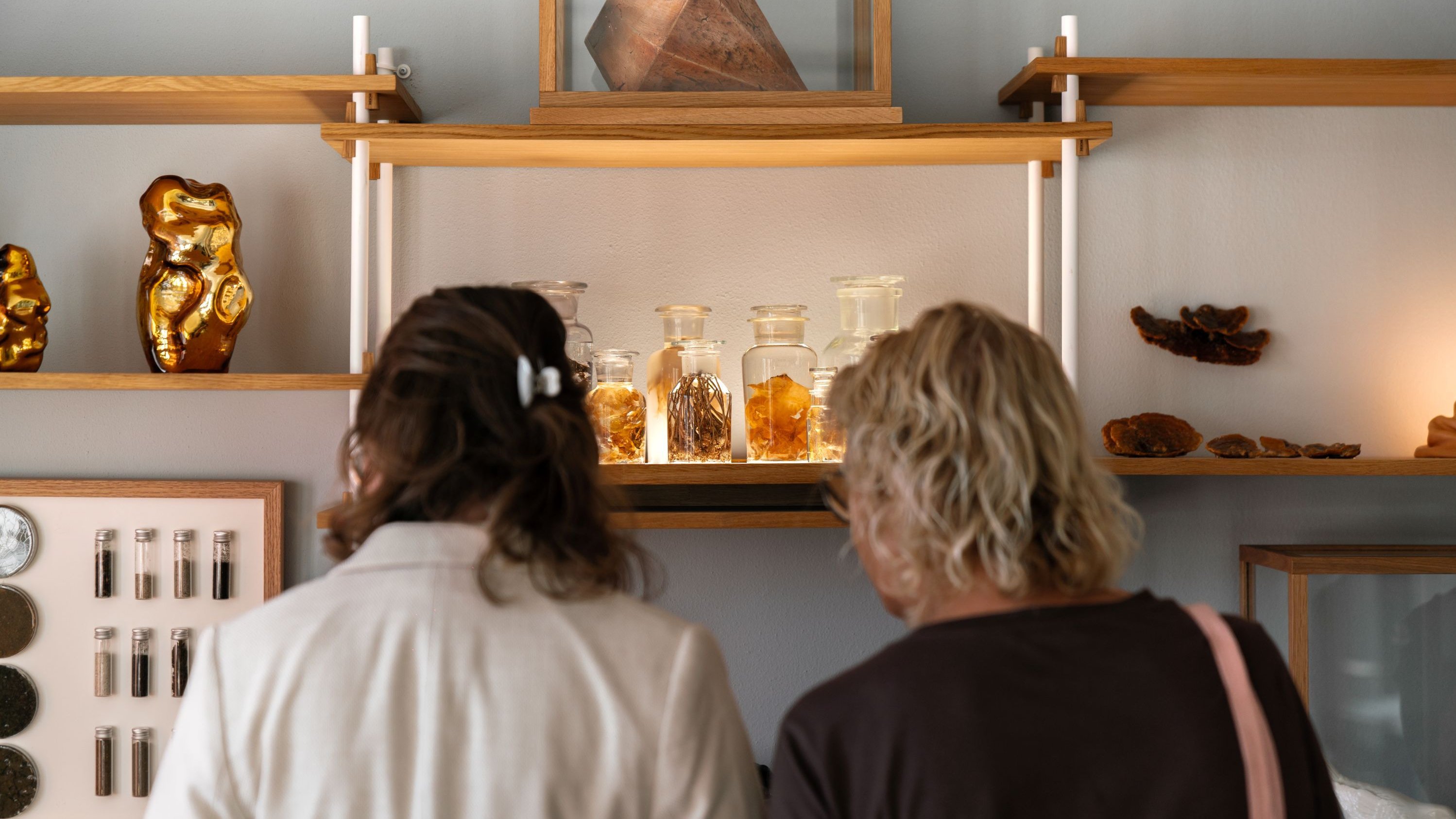 To kvinder kigger på kunstværk på en reol