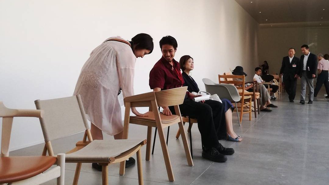 Gæster sætter sig i stole på udstilling 