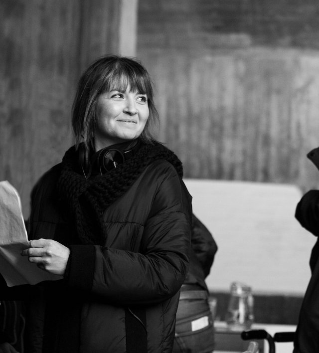 Kvinde står med papir i hånden og smiler