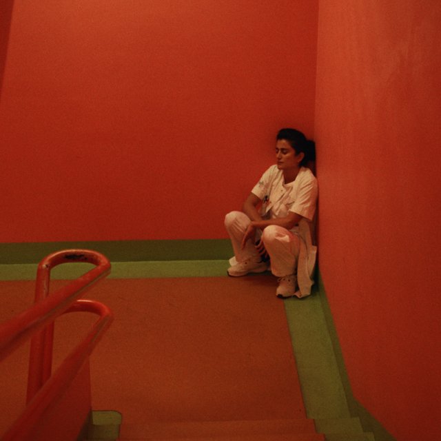 En kvinde sidder på hug i et hjørne af en trappeopgang. 