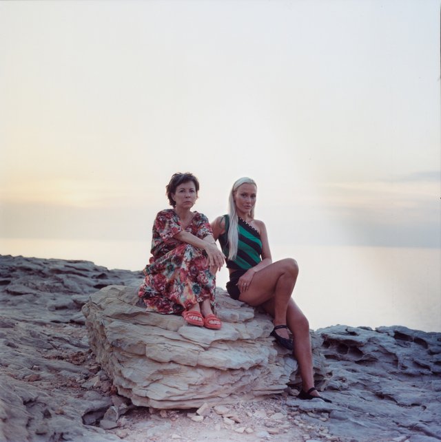 Two persons sitting on a big stone at sunset