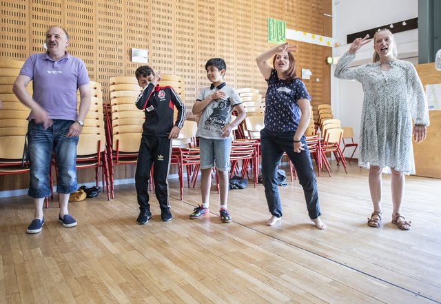 Tre børn og to voksne danser i en gymnastiksal