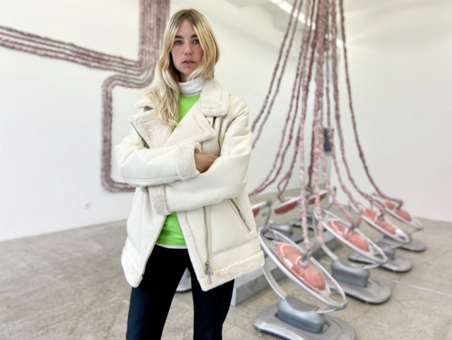 Kvinde står med kunstinstallation i baggrunden