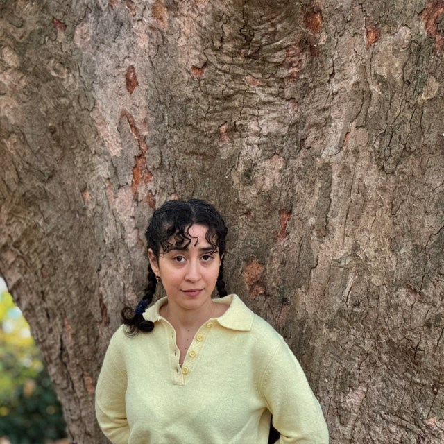 Portræt kvinde, som står ved et træ