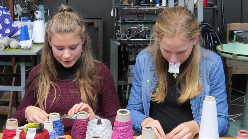 To unge piger arbejder ved et bord med garnnøgler