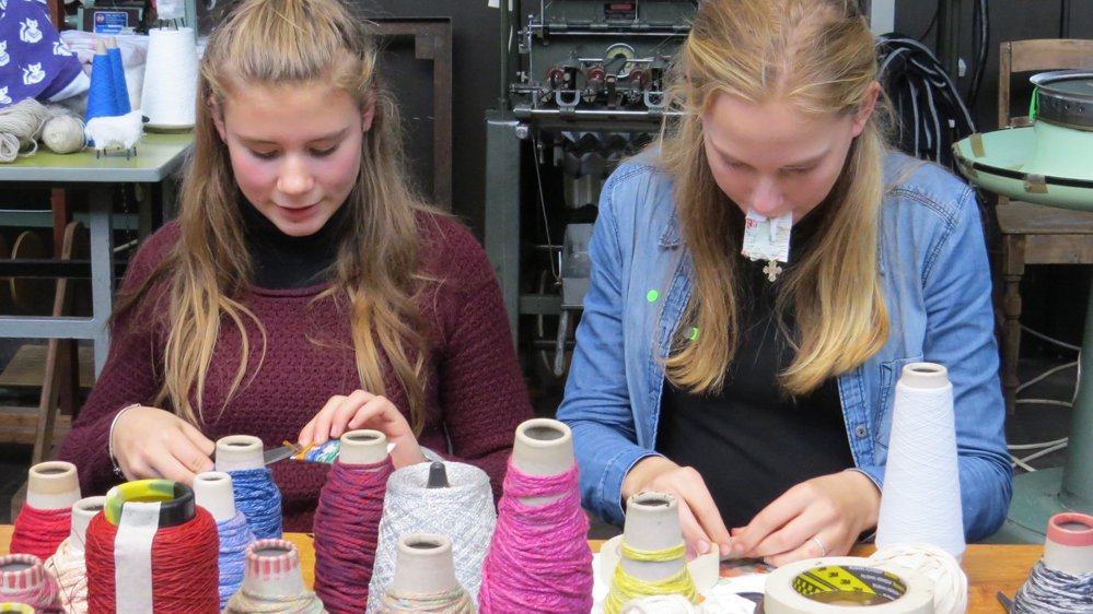 To unge piger arbejder ved et bord med garnnøgler